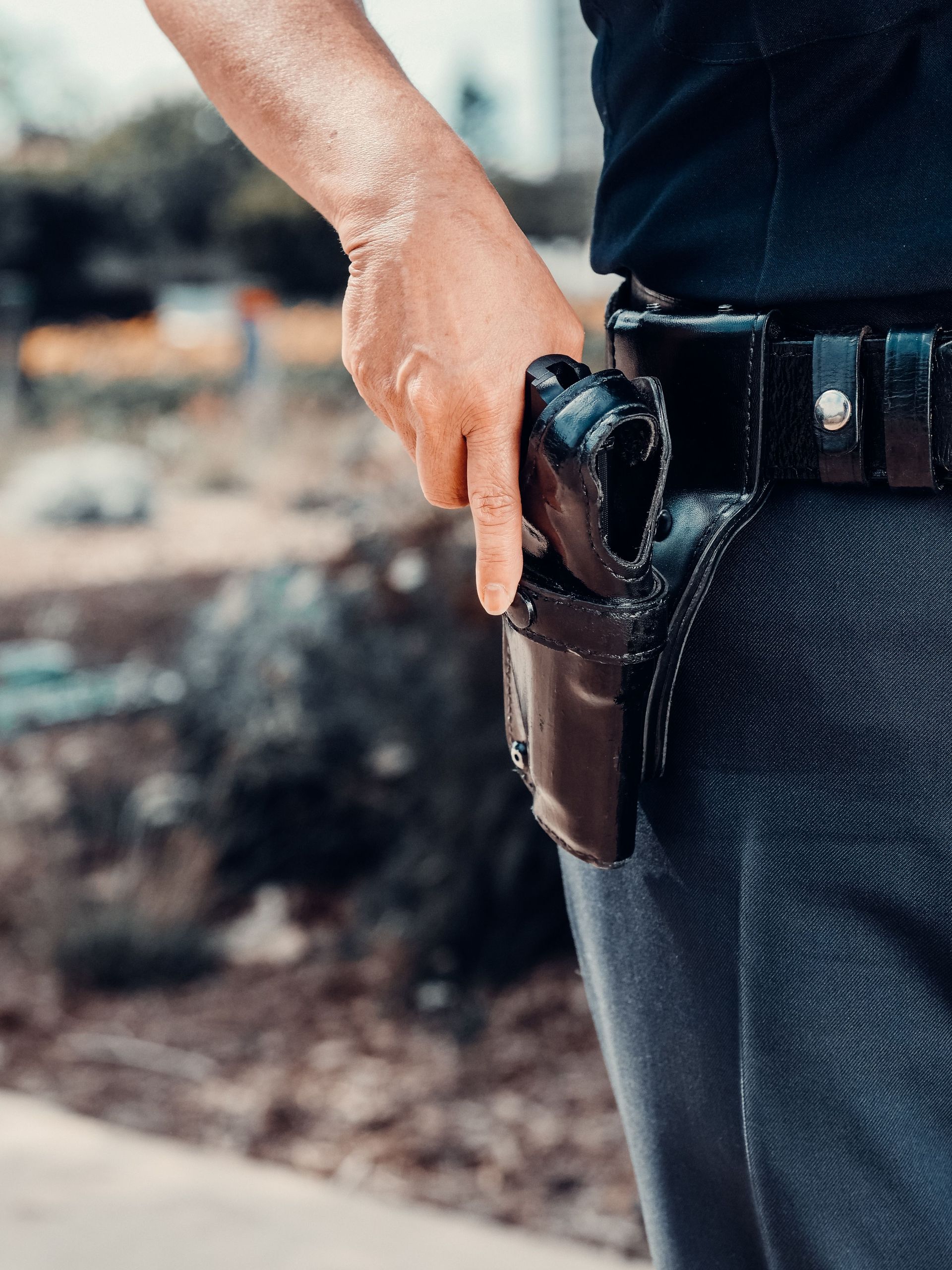 Close-up of a police officer's hand on a holstered gun, emphasizing security and law enforcement.
